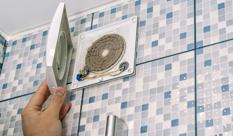 Hand of a man opening exhaust fan in bathroom