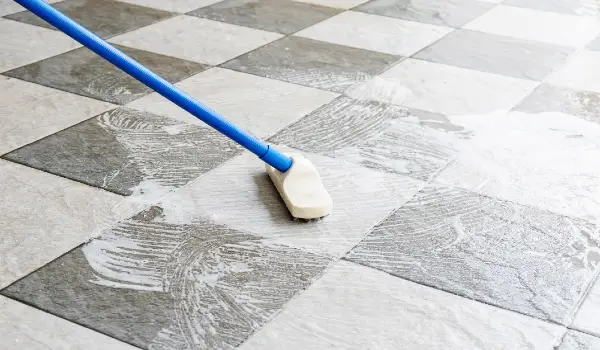 Clean the tile floor with a long-handled floor brush.