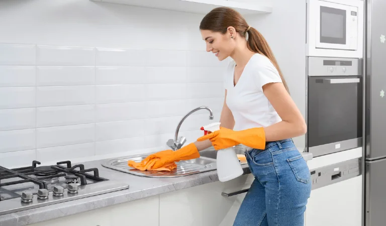 Young woman washing washbasin in protective gloves