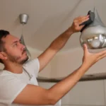 Closeup of man cleaning electric lamp with wet microfiber rag