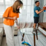 Happy woman sweeping the living room floor household concept