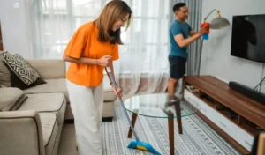 Happy woman sweeping the living room floor household concept