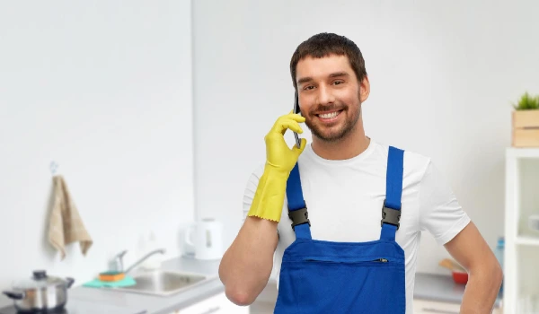 Male worker or cleaner calling on phone at kitchen